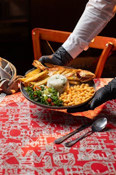 A vibrant Colombian seafood platter with fried fish, rice, plantains, and vegetables served in a restaurant setting.