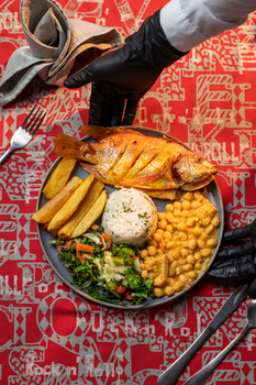 Colorful plate of fried mojarra fish with rice, plantains, and salad.